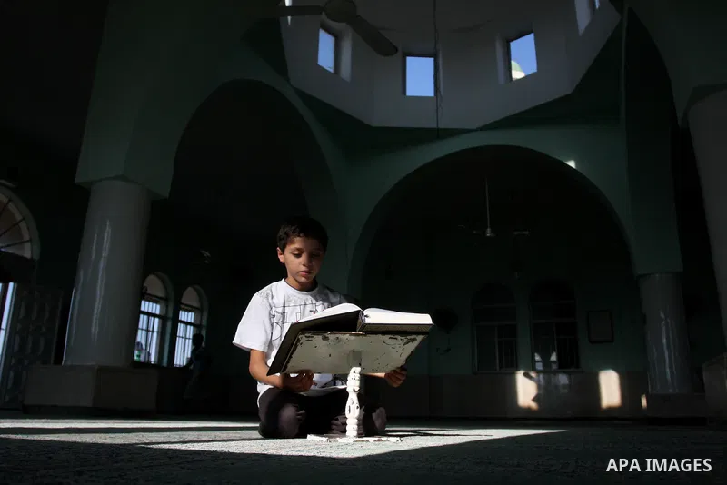 A Palestinian child reads the holy Qur'an at the mosque in West Bank City of Ramallah, on 25 July 2012. Muslims around the world refrain from eating, drinking and sexual intercourse from dawn till dusk during Ramadan, th...