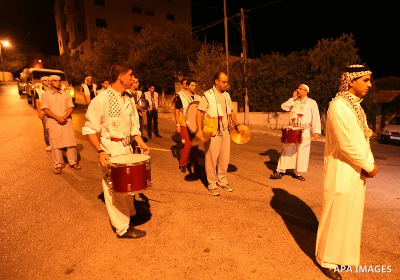 Palestinian youths volunteer of Red Crescent use a traditional drum to wake up people for their Suhoor in a narrow street in the West Bank City of Hebron on July 26, 2012. Photo by Mamoun Wazwazi