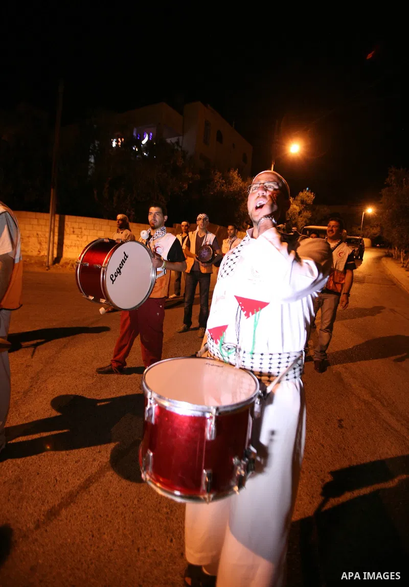 Palestinian youths volunteer of Red Crescent use a traditional drum to wake up people for their Suhoor in a narrow street in the West Bank City of Hebron on July 26, 2012. Photo by Mamoun Wazwazi