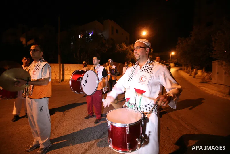 Palestinian youths volunteer of Red Crescent use a traditional drum to wake up people for their Suhoor in a narrow street in the West Bank City of Hebron on July 26, 2012. Photo by Mamoun Wazwazi