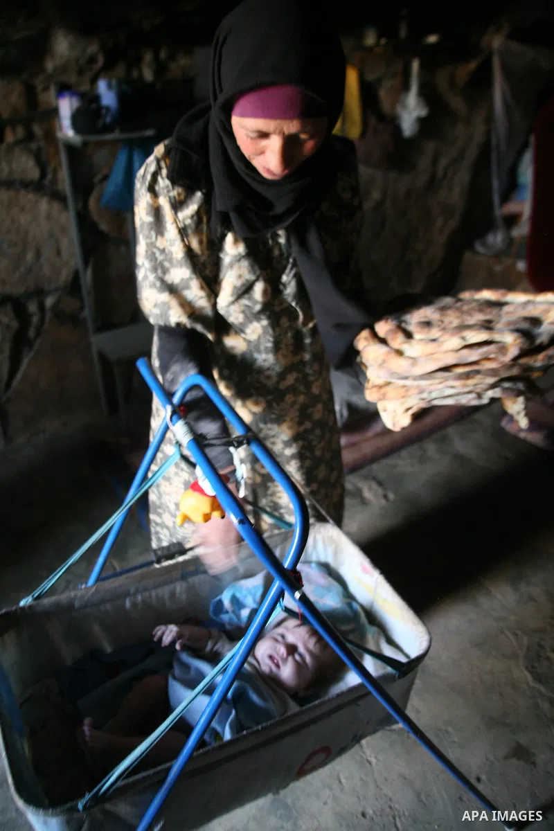 A Palestinian woman looks after her children in a cave, where they live, near the Palestinian village of Jimba, south of Yatta, near the West Bank town of Hebron on July 25, 2012. The Israeli Defence Minister, Ehud Barak...