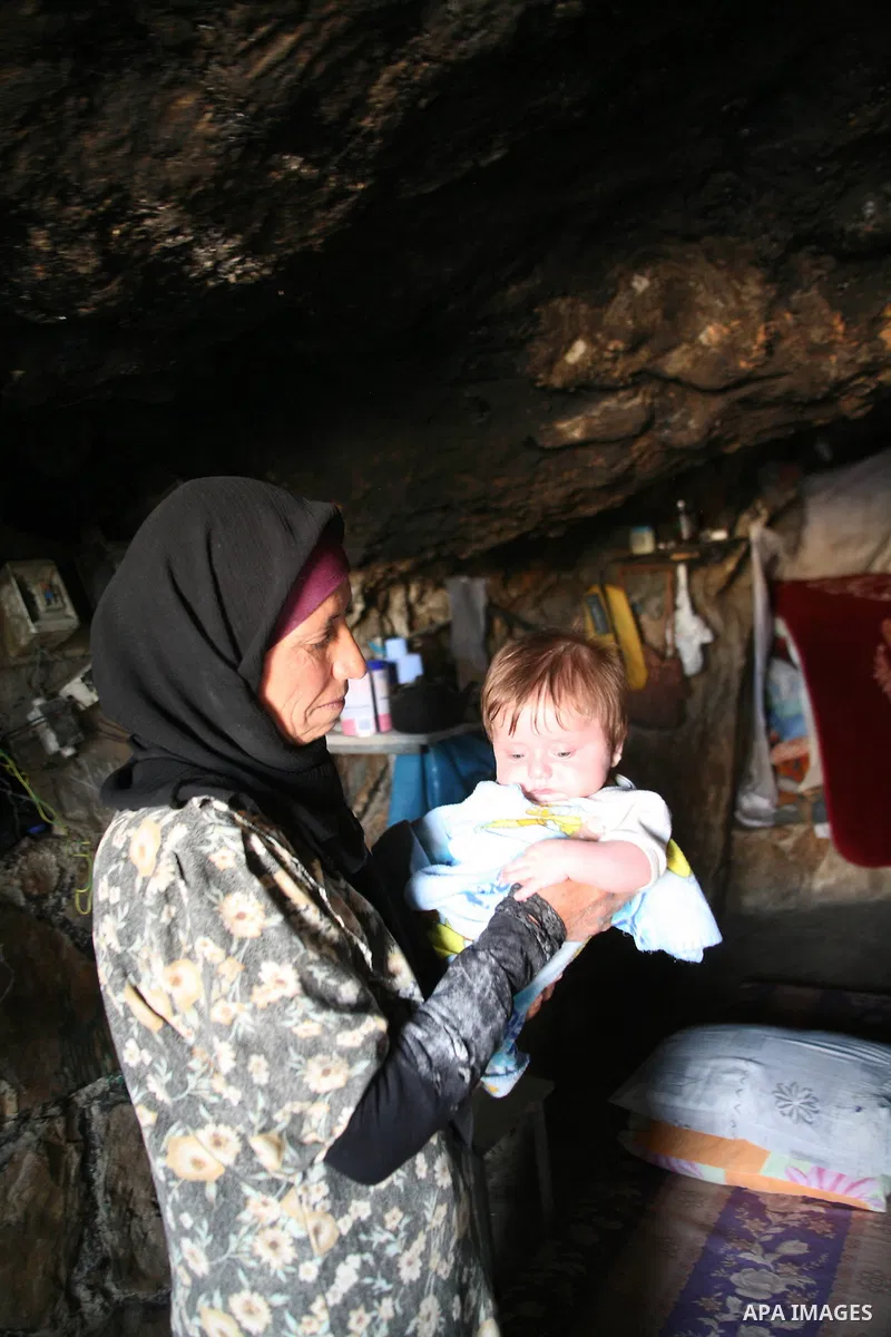 A Palestinian woman looks after her children in a cave, where they live, near the Palestinian village of Jimba, south of Yatta, near the West Bank town of Hebron on July 25, 2012. The Israeli Defence Minister, Ehud Barak...