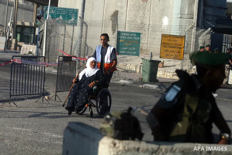 Palestinian disabled woman pass through Qalandiya checkpoint outside the West Bank city of Ramallah July 27, 2012, as she make her way to Jerusalem on the second Friday of the holy month of Ramadan. Photo by Issam Rimawi