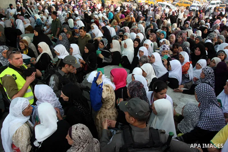 Palestinian women wait to show their identity cards to Israeli security officers at Qalandiya checkpoint outside the West Bank city of Ramallah July 27, 2012, as they make their way to Jerusalem on the second Friday of t...
