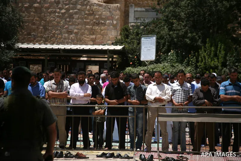 Israeli border policemen stand guard as Palestinian men perform the second Friday prayers of the Muslim fasting month of Ramadan outside the Ibrahimi Mosque or the Tomb of the Patriarchs in the West Bank city of Hebron o...