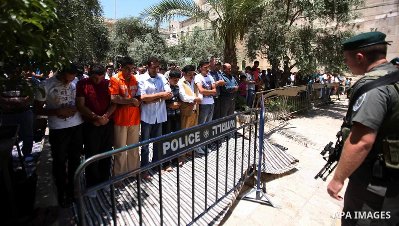 Israeli border policemen stand guard as Palestinian men perform the second Friday prayers of the Muslim fasting month of Ramadan outside the Ibrahimi Mosque or the Tomb of the Patriarchs in the West Bank city of Hebron o...