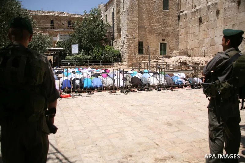 Israeli border policemen stand guard as Palestinian men perform the second Friday prayers of the Muslim fasting month of Ramadan outside the Ibrahimi Mosque or the Tomb of the Patriarchs in the West Bank city of Hebron o...