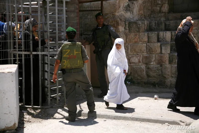 Israeli border policemen stand guard as Palestinian men perform the second Friday prayers of the Muslim fasting month of Ramadan outside the Ibrahimi Mosque or the Tomb of the Patriarchs in the West Bank city of Hebron o...