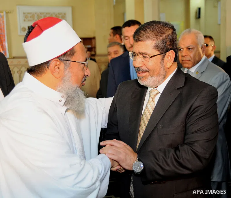 Egypt's President Mohamed Mursi (R) shakes hand with the imam of the mosque before Friday prayers during the Islamic holy month of Ramadan in Fayoum, about 100 km (60 miles) southeast of Cairo, July 27, 2012. Photo by Eg...