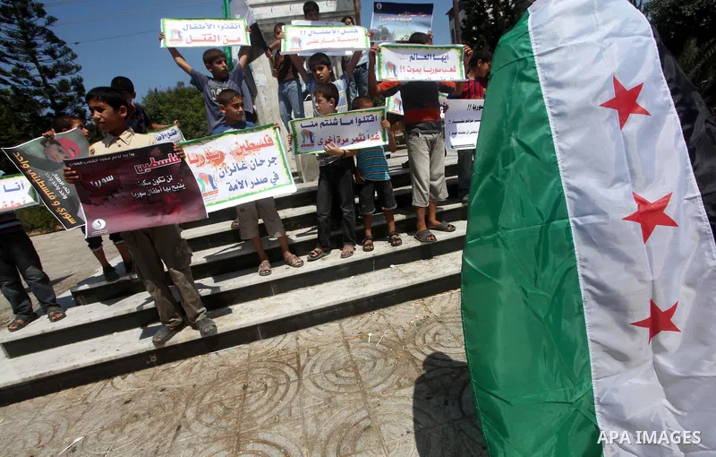 Palestinian children hold a Syrian revolution flag during a protest against Syria's President Bashar al-Assad and support of Syrian Children at the Al joundi Al Majhoul in Gaza City on July 28, 2012. Photo by Ashraf Amra