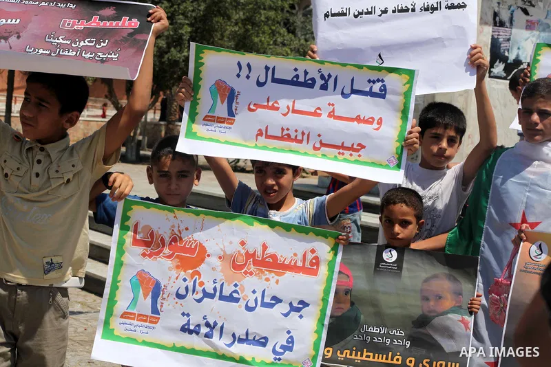 Palestinian children hold a Syrian revolution flag during a protest against Syria's President Bashar al-Assad and support of Syrian Children at the Al joundi Al Majhoul in Gaza City on July 28, 2012. Photo by Ashraf Amra