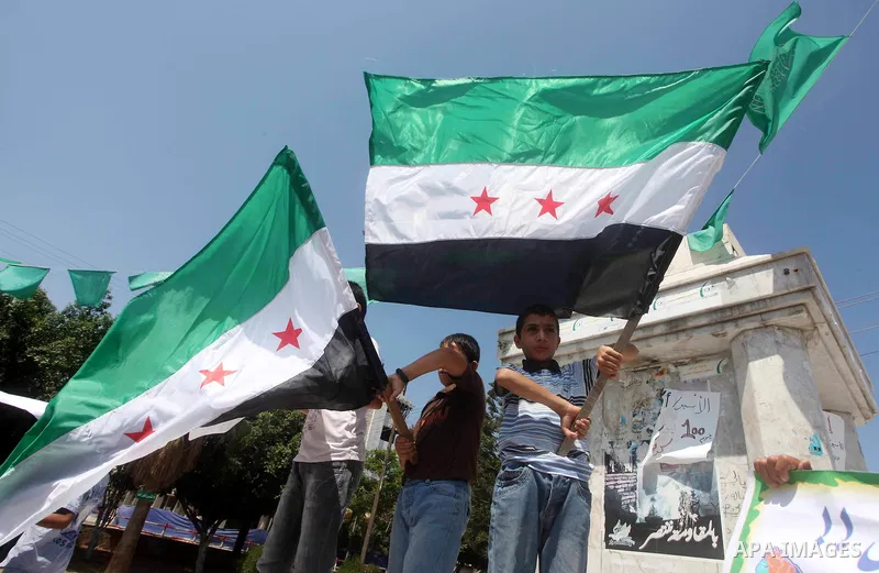 Palestinian children hold a Syrian revolution flag during a protest against Syria's President Bashar al-Assad and support of Syrian Children at the Al joundi Al Majhoul in Gaza City on July 28, 2012. Photo by Ashraf Amra