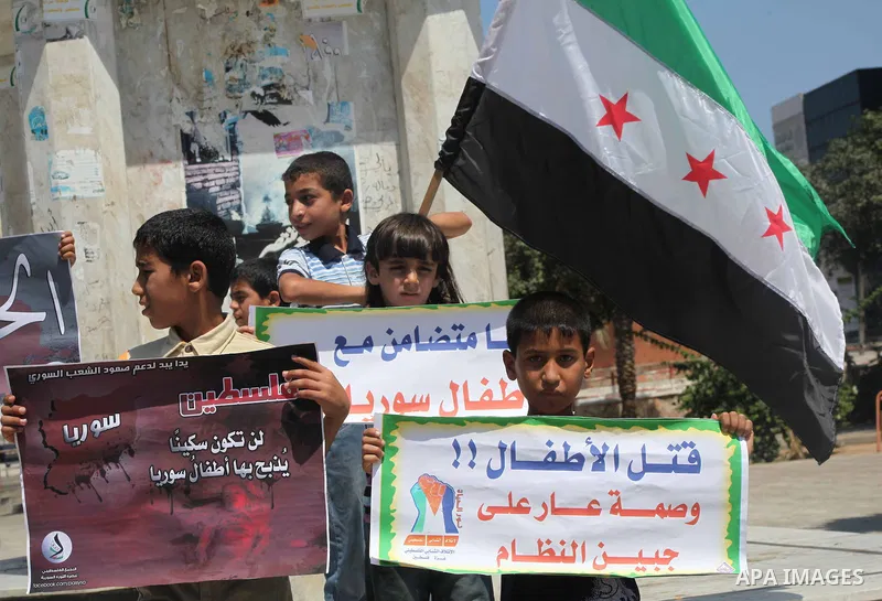 Palestinian children hold a Syrian revolution flag during a protest against Syria's President Bashar al-Assad and support of Syrian Children at the Al joundi Al Majhoul in Gaza City on July 28, 2012. Photo by Ashraf Amra