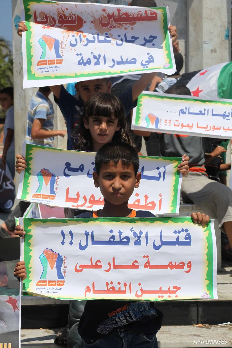 Palestinian children hold a Syrian revolution flag during a protest against Syria's President Bashar al-Assad and support of Syrian Children at the Al joundi Al Majhoul in Gaza City on July 28, 2012. Photo by Ashraf Amra