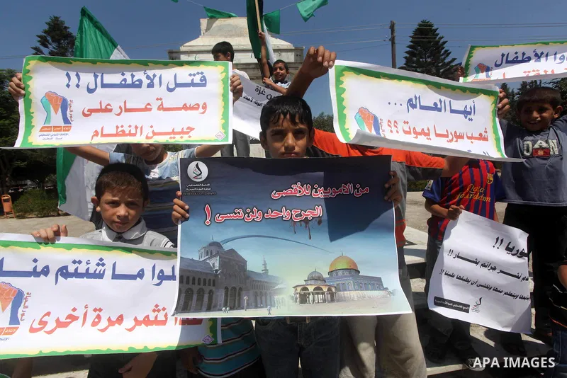 Palestinian children hold a Syrian revolution flag during a protest against Syria's President Bashar al-Assad and support of Syrian Children at the Al joundi Al Majhoul in Gaza City on July 28, 2012. Photo by Ashraf Amra