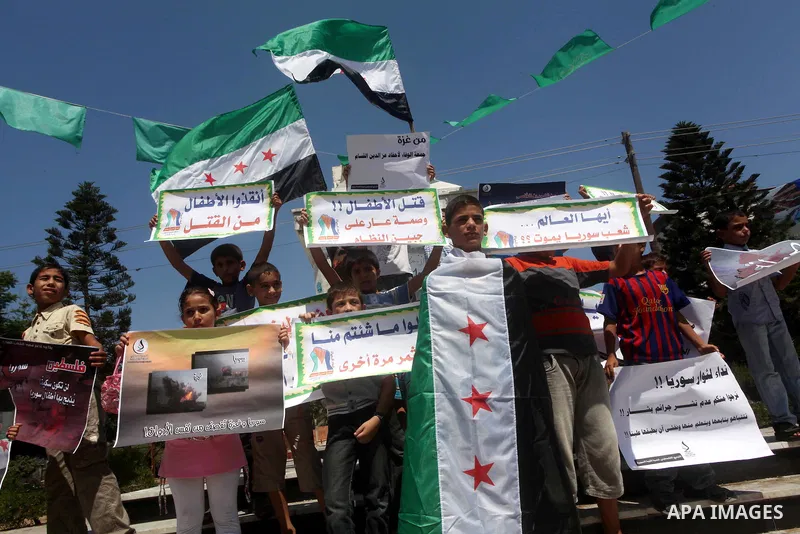 Palestinian children hold a Syrian revolution flag during a protest against Syria's President Bashar al-Assad and support of Syrian Children at the Al joundi Al Majhoul in Gaza City on July 28, 2012. Photo by Ashraf Amra