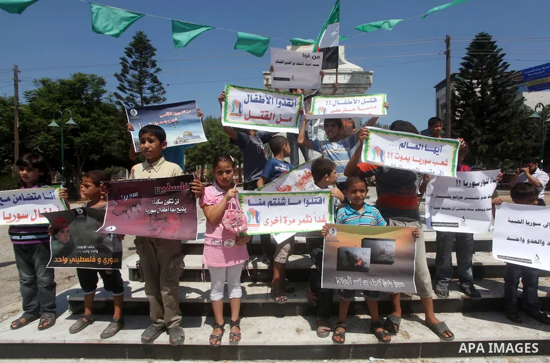 Palestinian children hold a Syrian revolution flag during a protest against Syria's President Bashar al-Assad and support of Syrian Children at the Al joundi Al Majhoul in Gaza City on July 28, 2012. Photo by Ashraf Amra