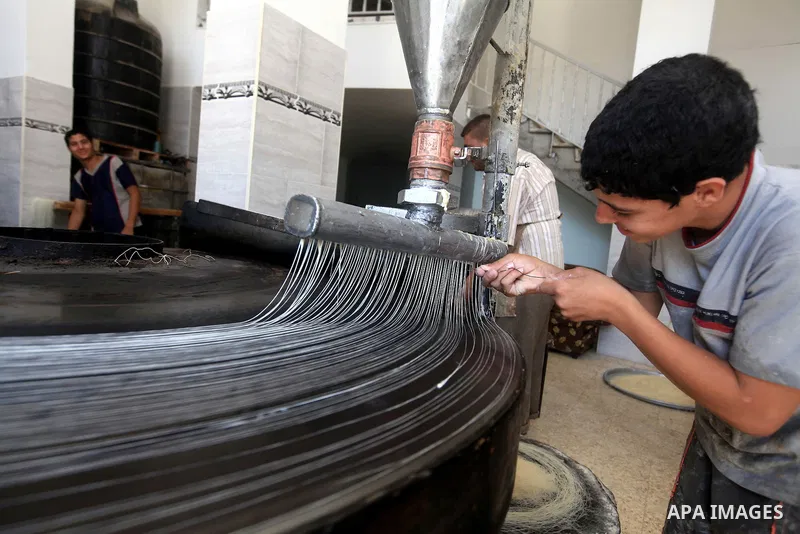 A Palestinian youth makes Konafa in Gaza city on 28 July 2012. Palestinians gets ready for break their fast "Eftar" after long hours of fasting. Bakers make Konafa and traditional pastry known as ''Qatayef'' which is con...