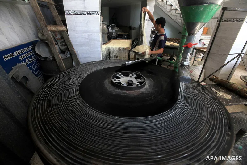 A Palestinian youth makes Konafa in Gaza city on 28 July 2012. Palestinians gets ready for break their fast "Eftar" after long hours of fasting. Bakers make Konafa and traditional pastry known as ''Qatayef'' which is con...