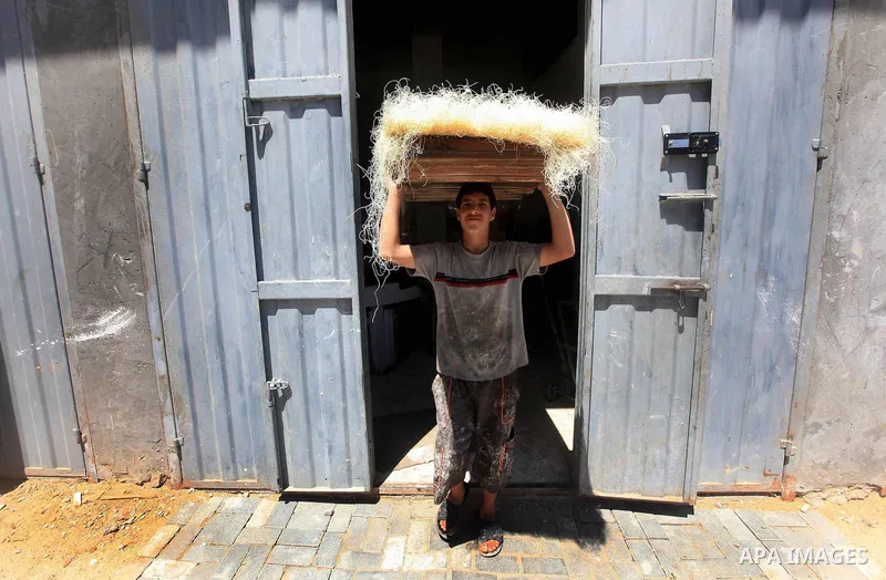A Palestinian youth holds tray of the dough used in making Konafa in Gaza city on 28 July 2012. Palestinians gets ready for break their fast "Eftar" after long hours of fasting. Bakers make Konafa and traditional pastry...