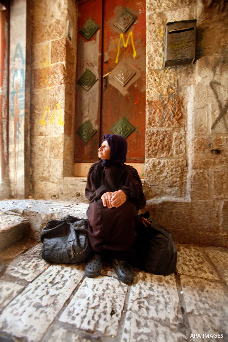 A Palestinian indigent woman waits to recieve food from volunteers during the fasting month of Ramadan in Jerusalem on July 28, 2012. During Ramadan eating, drinking, sex and smoking is banned and restaurants are forbidd...