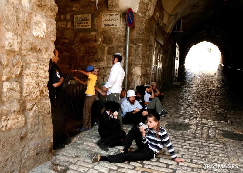 Israeli policemen guard a group of Jewish settlers as they stop Palestinians walk pass of Bab Hutta road, in Jerusalem old city, on 29 July 2012. Photo by Mahfouz Abu Turk