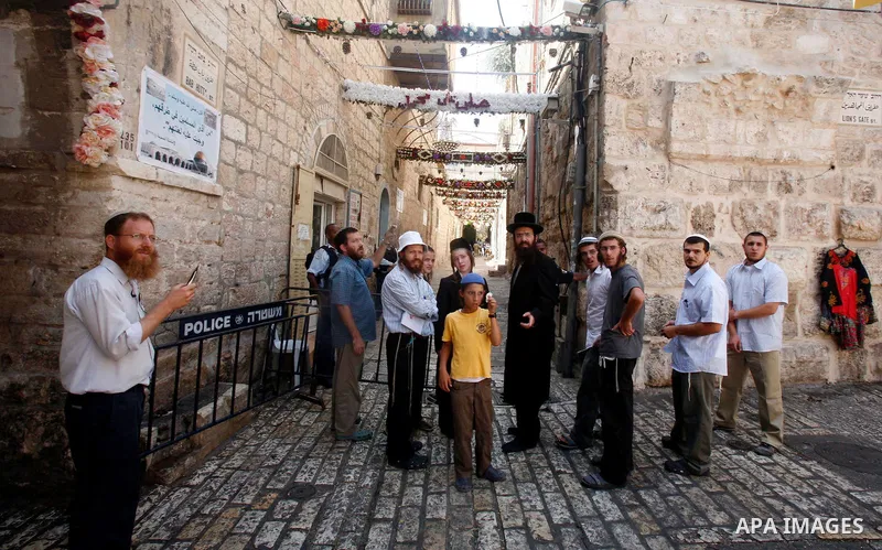 Israeli policemen guard a group of Jewish settlers as they stop Palestinians walk pass of Bab Hutta road, in Jerusalem old city, on 29 July 2012. Photo by Mahfouz Abu Turk
