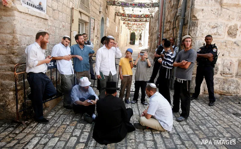 Israeli policemen guard a group of Jewish settlers as they stop Palestinians walk pass of Bab Hutta road, in Jerusalem old city, on 29 July 2012. Photo by Mahfouz Abu Turk