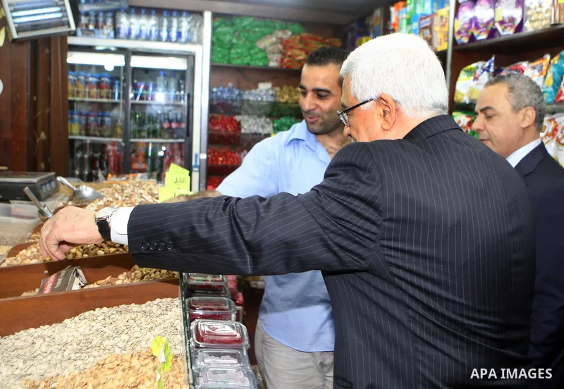 Palestinian President Mahmoud Abbas (abu mazen) tastes nuts in a shop during a tour of Ramallah city in the West Bank in the holy month of Ramadan, on 29 July 2012. Photo by Thaer Ganaim