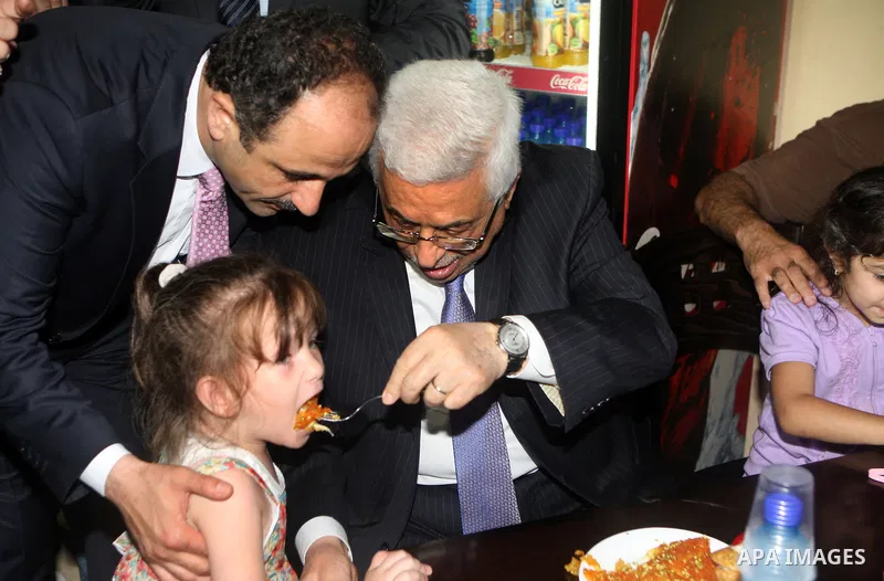 Palestinian President Mahmoud Abbas (abu mazen) feeds a Palestinian girl in a restaurant during a tour of Ramallah city in the West Bank in the holy month of Ramadan, on 29 July 2012. Photo by Thaer Ganaim