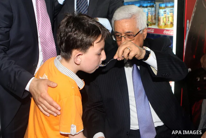 Palestinian President Mahmoud Abbas (abu mazen) feeds a Palestinian child in a restaurant during a tour of Ramallah city in the West Bank in the holy month of Ramadan, on 29 July 2012. Photo by Thaer Ganaim