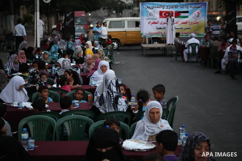 Families of Palestinian prisoners in Israeli jails attend the collective breaking fast organized by the Association of "Wa'ed" and funded by the Turkish relief "IHH" in front of the Red Cross headquarters during the holy...