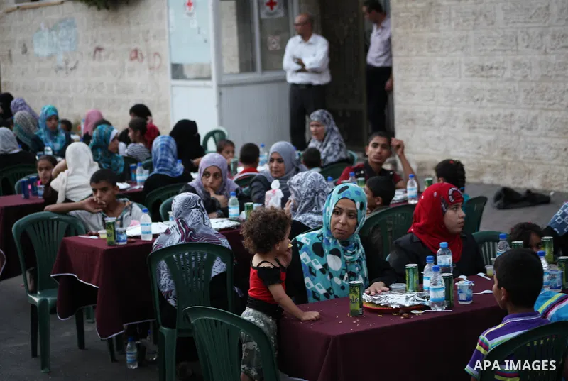 Families of Palestinian prisoners in Israeli jails attend the collective breaking fast organized by the Association of "Wa'ed" and funded by the Turkish relief "IHH" in front of the Red Cross headquarters during the holy...