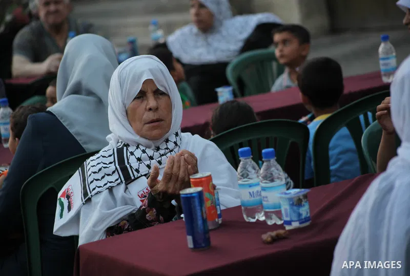 Families of Palestinian prisoners in Israeli jails attend the collective breaking fast organized by the Association of "Wa'ed" and funded by the Turkish relief "IHH" in front of the Red Cross headquarters during the holy...