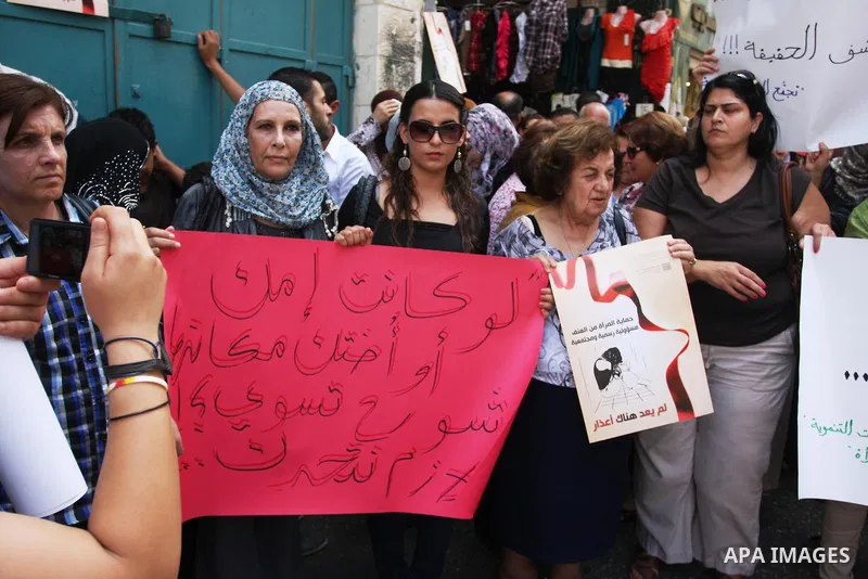 Palestinian women hold signs during a demonstration protesting violence against women held at the spot where a woman's throat was allegedly slashed by her husband on Monday, in the West Bank town of Bethlehem, Wednesday,...
