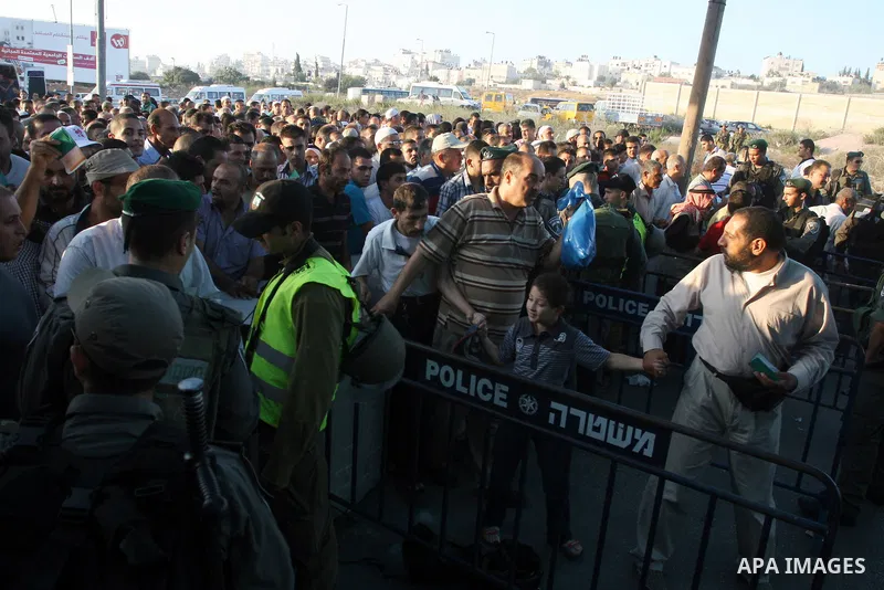 Palestinian men show their ID cards to an Israeli border policeman as they wait to cross through an military checkpoint on their way to pray at the al-Aqsa Mosque in Jerusalem, on the third Friday of the Muslim holy mont...