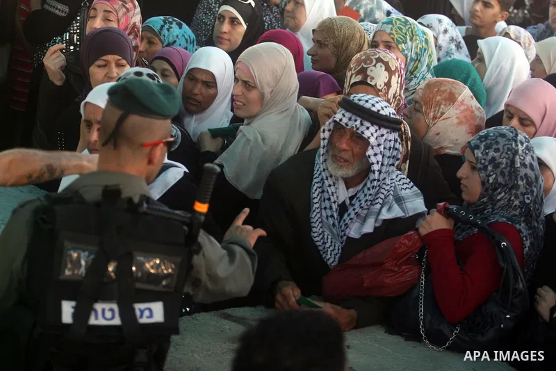 Palestinian men show their ID cards to an Israeli border policeman as they wait to cross through an military checkpoint on their way to pray at the al-Aqsa Mosque in Jerusalem, on the third Friday of the Muslim holy mont...