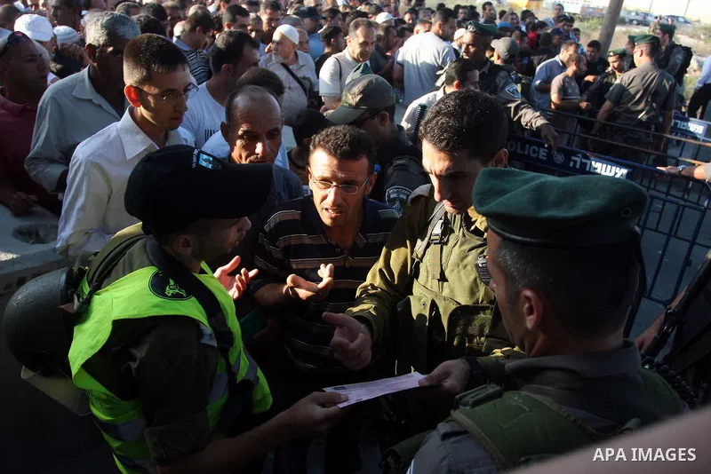 Palestinian men show their ID cards to an Israeli border policeman as they wait to cross through an military checkpoint on their way to pray at the al-Aqsa Mosque in Jerusalem, on the third Friday of the Muslim holy mont...