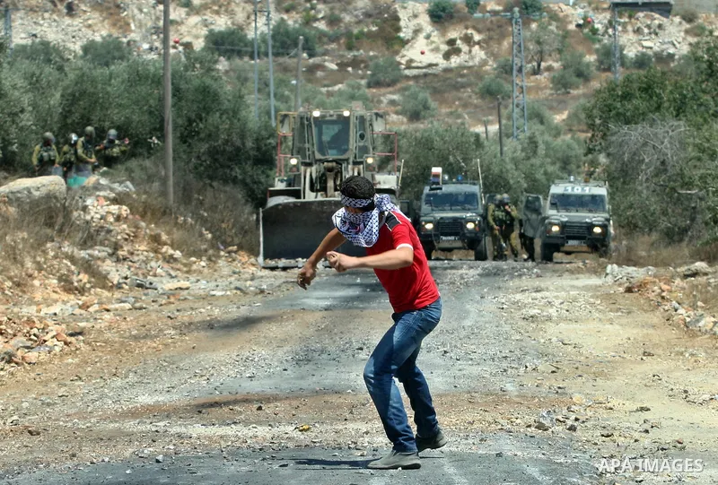 A Palestinian protestor throws stones at Israeli truck during a demonstration against the expropriation of Palestinian land by Israel in the village of Kafr Qaddum, near the West Bank city of Nablus on Aug. 03, 2012. Pho...