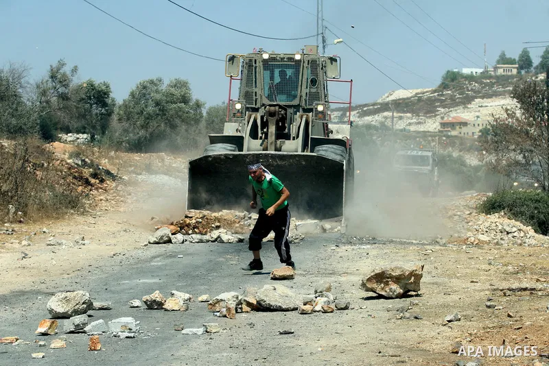 A Palestinian protestor throws stones at Israeli truck during a demonstration against the expropriation of Palestinian land by Israel in the village of Kafr Qaddum, near the West Bank city of Nablus on Aug. 03, 2012. Pho...