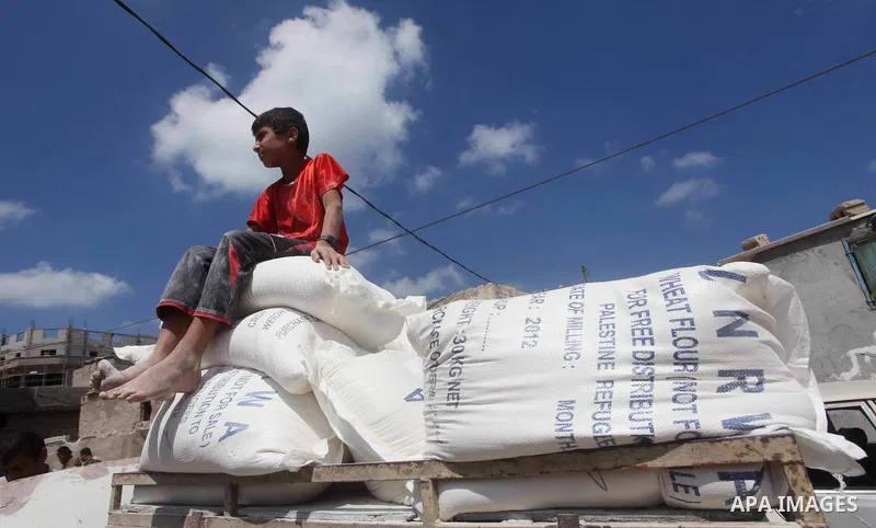 A Palestinian youth carries a sack of flour at a UN Relief and Works Agency (UNRWA) warehouse in the Shati refugee camp, in Gaza City, on Aug. 05, 2012. UNRWA launched Sunday its Gaza Ramadan Appeal for 5000 food parcels...