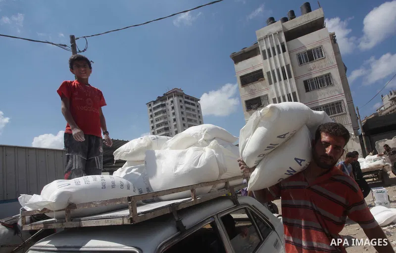 A Palestinian youth carries a sack of flour at a UN Relief and Works Agency (UNRWA) warehouse in the Shati refugee camp, in Gaza City, on Aug. 05, 2012. UNRWA launched Sunday its Gaza Ramadan Appeal for 5000 food parcels...