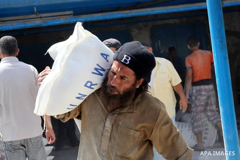 A Palestinian man carries a sack of flour at a UN Relief and Works Agency (UNRWA) warehouse in the Shati refugee camp, in Gaza City, on Aug. 05, 2012. UNRWA launched Sunday its Gaza Ramadan Appeal for 5000 food parcels i...