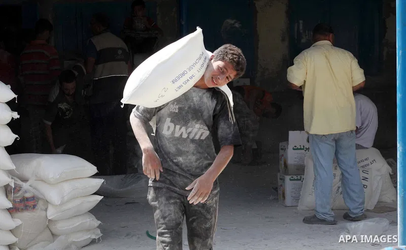 A Palestinian youth carries a sack of flour at a UN Relief and Works Agency (UNRWA) warehouse in the Shati refugee camp, in Gaza City, on Aug. 05, 2012. UNRWA launched Sunday its Gaza Ramadan Appeal for 5000 food parcels...