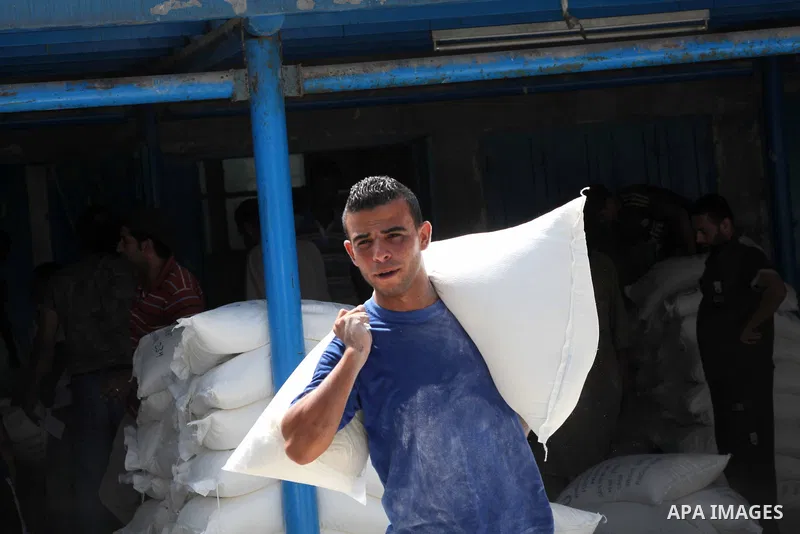 A Palestinian youth carries a sack of flour at a UN Relief and Works Agency (UNRWA) warehouse in the Shati refugee camp, in Gaza City, on Aug. 05, 2012. UNRWA launched Sunday its Gaza Ramadan Appeal for 5000 food parcels...