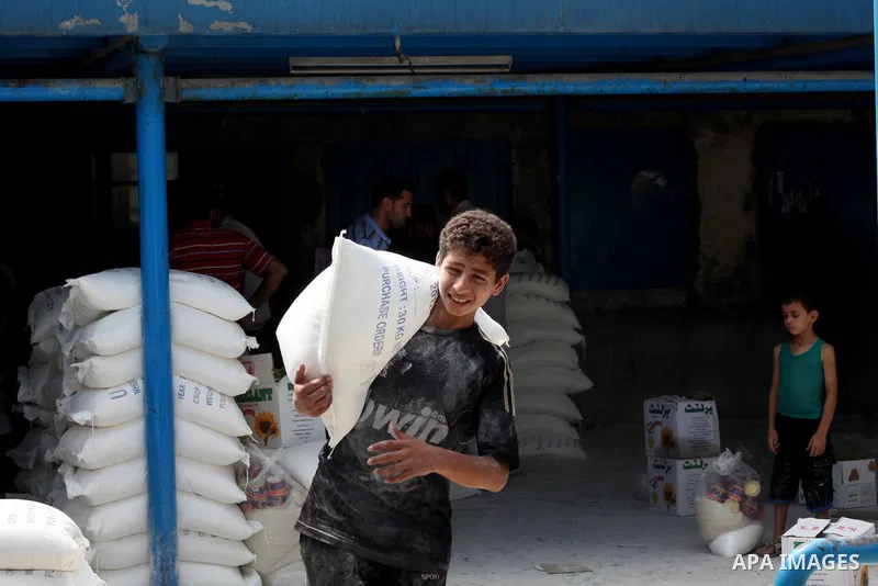 A Palestinian youth carries a sack of flour at a UN Relief and Works Agency (UNRWA) warehouse in the Shati refugee camp, in Gaza City, on Aug. 05, 2012. UNRWA launched Sunday its Gaza Ramadan Appeal for 5000 food parcels...