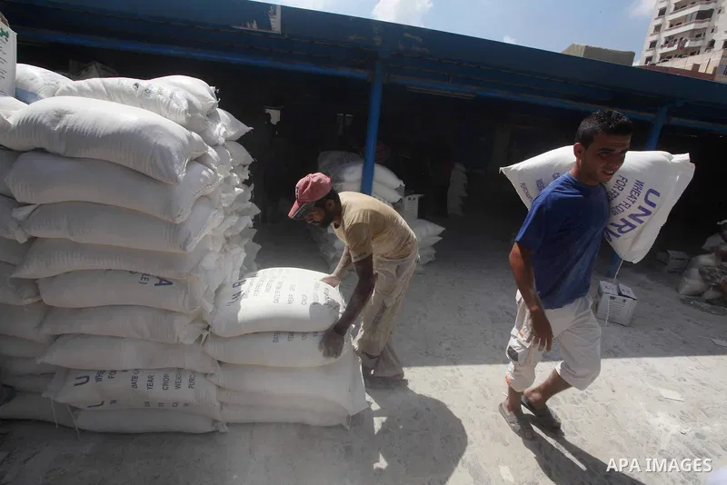 A Palestinian youth carries a sack of flour at a UN Relief and Works Agency (UNRWA) warehouse in the Shati refugee camp, in Gaza City, on Aug. 05, 2012. UNRWA launched Sunday its Gaza Ramadan Appeal for 5000 food parcels...