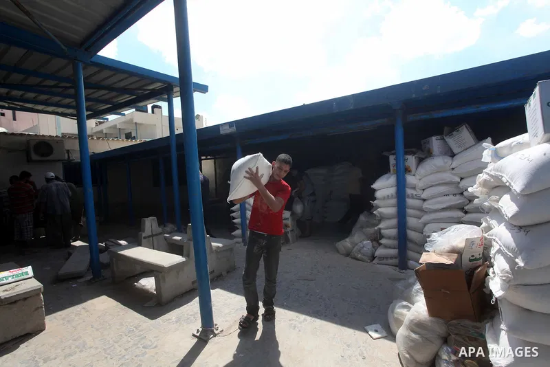 A Palestinian youth carries a sack of flour at a UN Relief and Works Agency (UNRWA) warehouse in the Shati refugee camp, in Gaza City, on Aug. 05, 2012. UNRWA launched Sunday its Gaza Ramadan Appeal for 5000 food parcels...