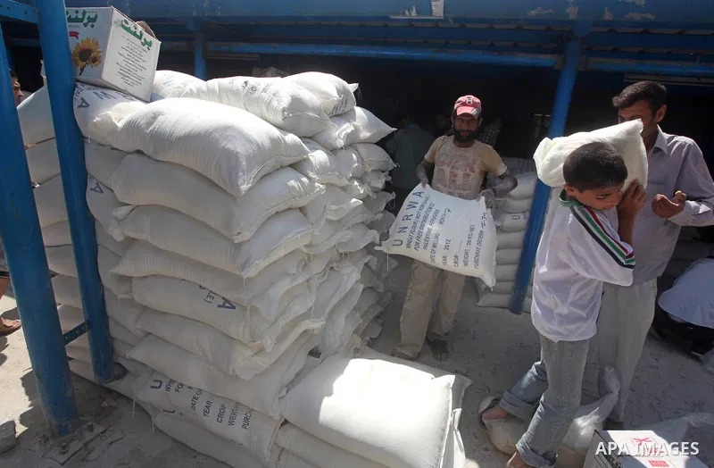 A Palestinian man carries a sack of flour at a UN Relief and Works Agency (UNRWA) warehouse in the Shati refugee camp, in Gaza City, on Aug. 05, 2012. UNRWA launched Sunday its Gaza Ramadan Appeal for 5000 food parcels i...