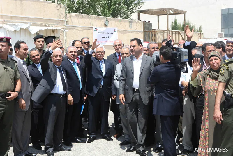 Palestinian President Mahmoud Abbas, os accompanied by other officials as he waves to a convoy of trucks carrying food and medical supplies, which reportedly were provided by the Palestinian people, leaving Ramallah boun...